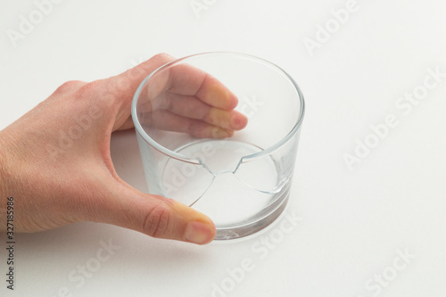 broken white glass and hand on the white background.Injury due to glass breakage.damages of drinking water with broken glass.