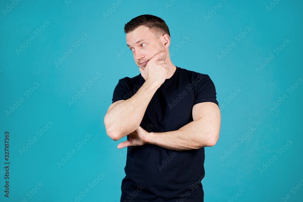 sporty young man looks away and holds his chin sporty young man looks away and holds his chin