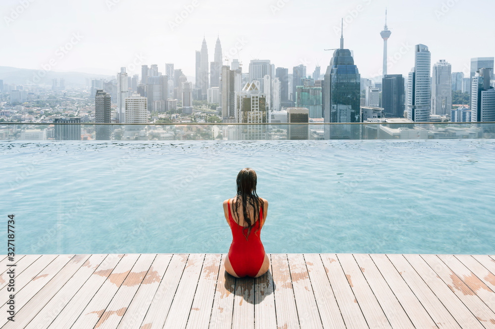 Woman sitting in the infinity pool watching the city of Kuala Lumpur