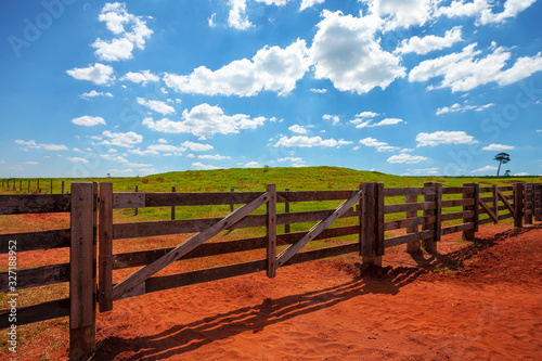 porteira da fazenda com céu azul, porteira de madeira, terra vermelha photo