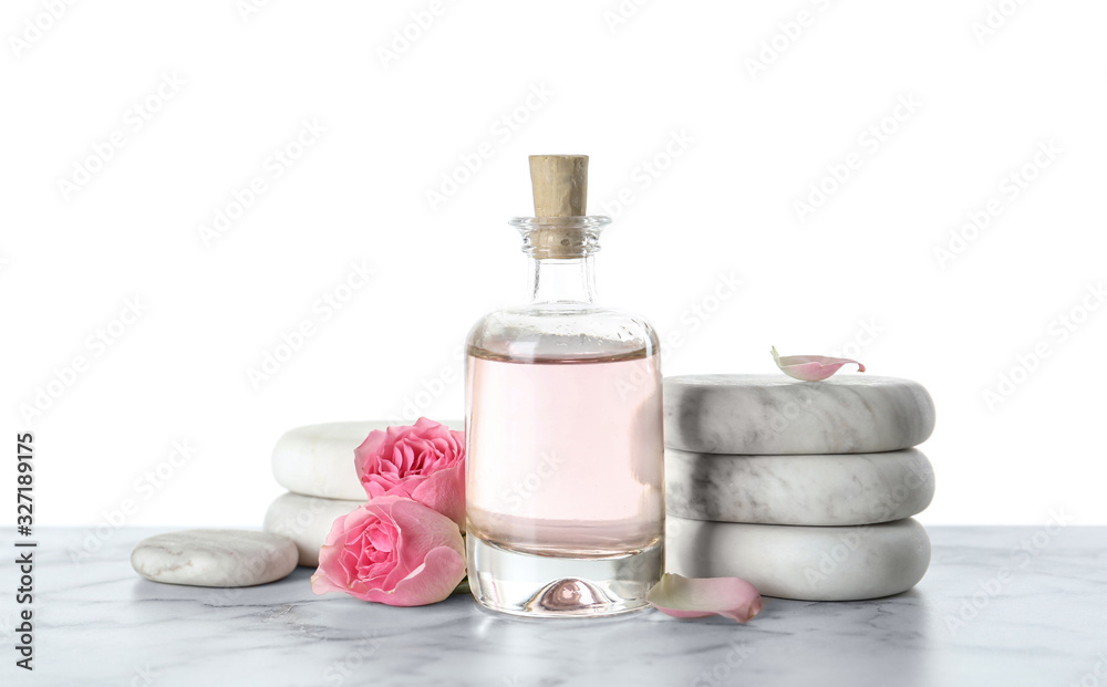 Bottle of essential oil, flowers and stones on marble table Bottle of essential oil, flowers and stones on marble table