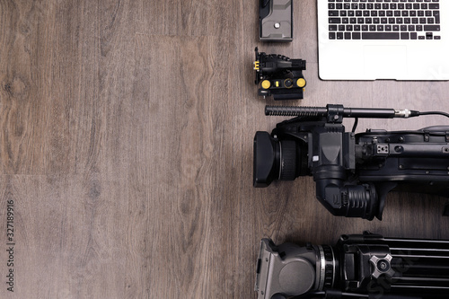 Flat lay composition with video camera and other equipment on wooden table. Space for text