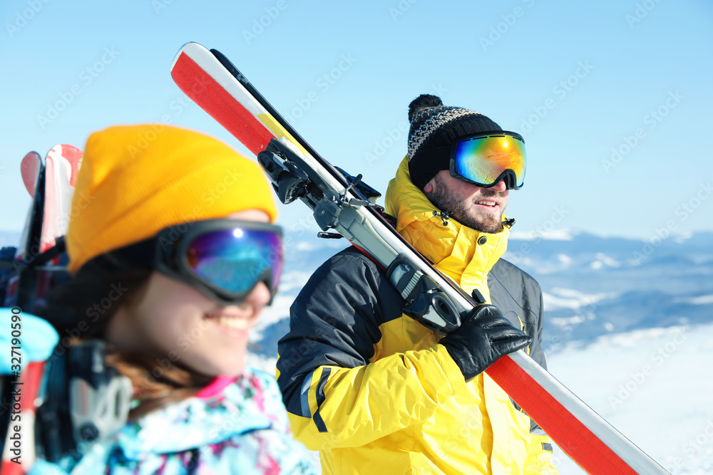 Happy couple with ski equipment in mountains. Winter vacation