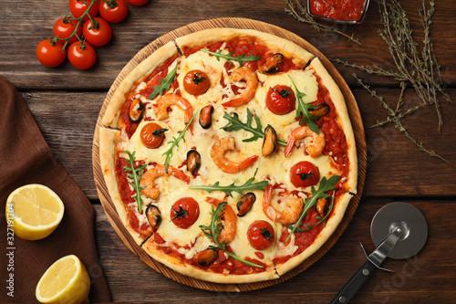 Delicious seafood pizza on wooden table, flat lay