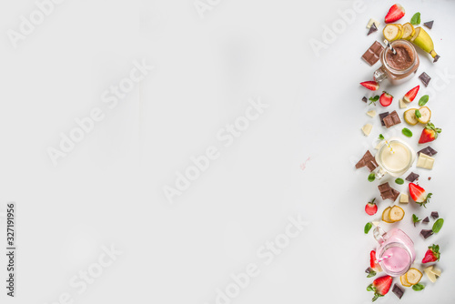 Three mason jars with milkshakes or smoothie. Summer healthy breakfast, lunch drinks - banana, chocolate and strawberry milkshakes on wooden background © ricka_kinamoto