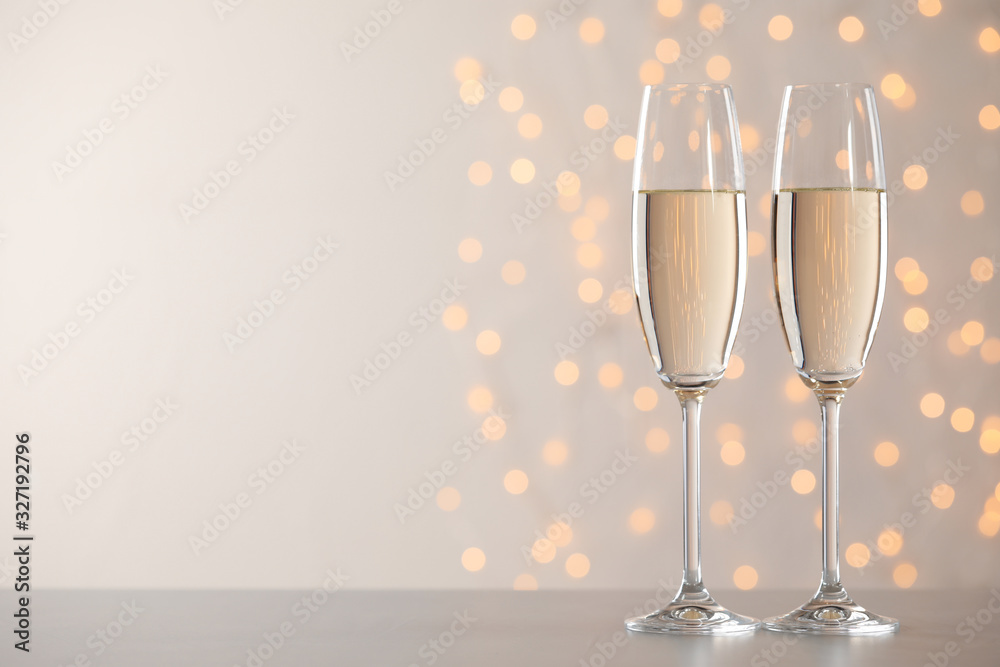 Glasses of champagne on grey table against blurred lights. Space for text Glasses of champagne on grey table against blurred lights. Space for text