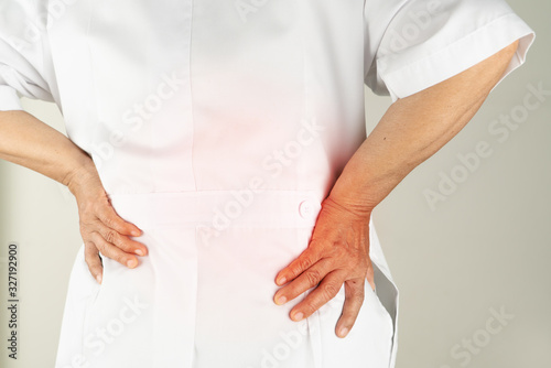 senior doctor woman suffering of backache, touching back with hand, muscular pain over white background