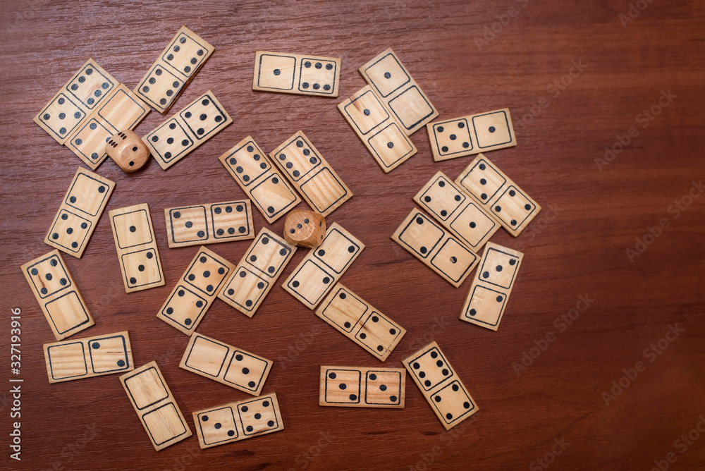 A game for the whole family - dominoes, chaotic lies on a wooden background, top view A game for the whole family - dominoes, chaotic lies on a wooden background, top view