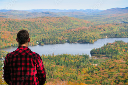 Back view of a man with a lumberjack shirt and admiring the beautiful autumn colours in the Mont-Tremblant national park 