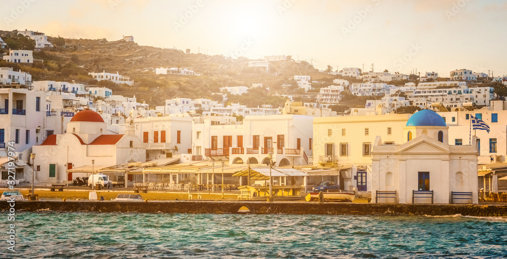 Beautiful panoramic seafront with greek churches of Mykonos at sunset, view from the sea