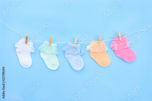 Colorful cute baby socks hanging on the clothesline on blue background. Baby accessories. Flat lay.