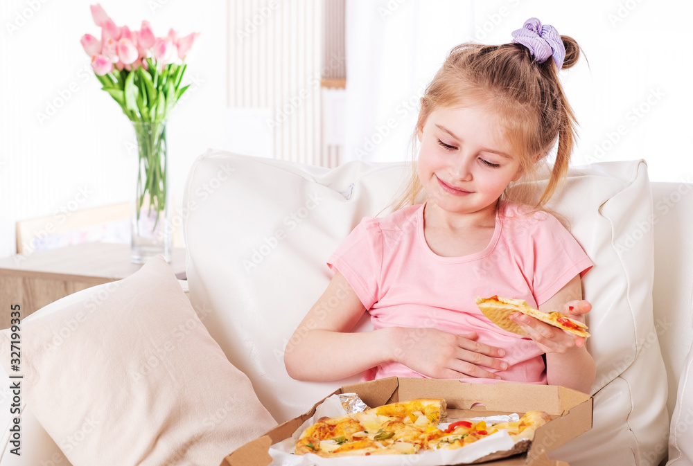 Smiling little girl eating pizza, on the couch Smiling little girl eating pizza, on the couch