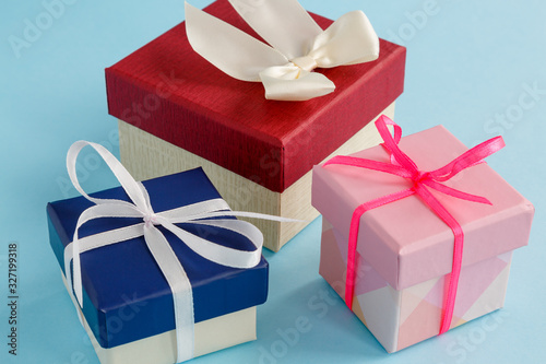 Gift boxes in blue, pink and Burgundy colors on a light blue background.  Selective focus.