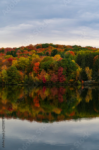 Colorful and autumnal trees reflecting in the water, at the St Bruno national park, Quebec