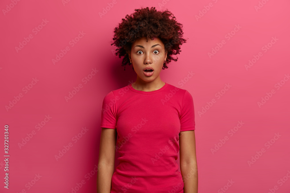Speechless shocked woman gasps from fear, realizes she forgot passport while arrives at airport, stands stunned and impressed, wears casual t shirt, poses over pink background, stares at camera Speechless shocked woman gasps from fear, realizes she forgot passport while arrives at airport, stands stunned and impressed, wears casual t shirt, poses over pink background, stares at camera