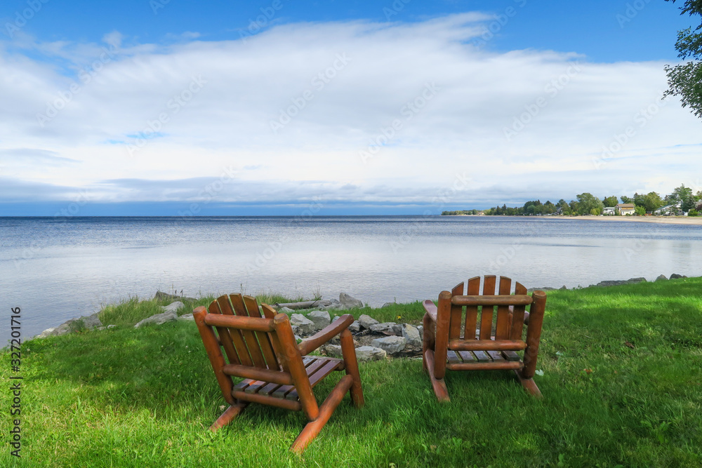 Peaceful view of two wooden chairs facing the lac St Jean, in Quebec