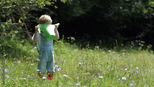 Amusing little boy look in big water can, beatific blossom nature