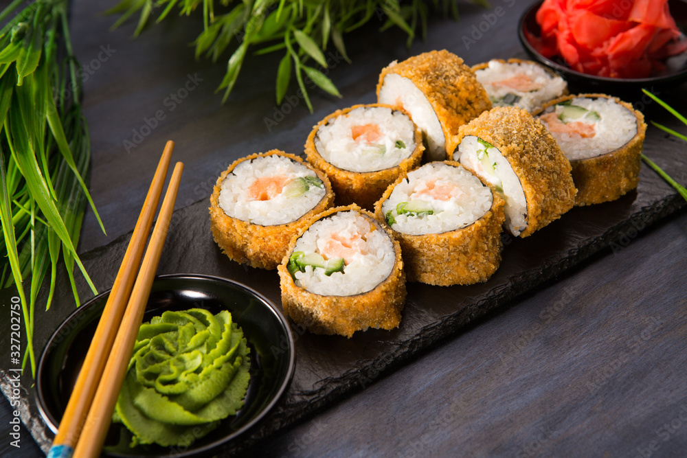 Set of baked sushi rolls with wasabi and ginger on a black background. Japanese oriental cuisine