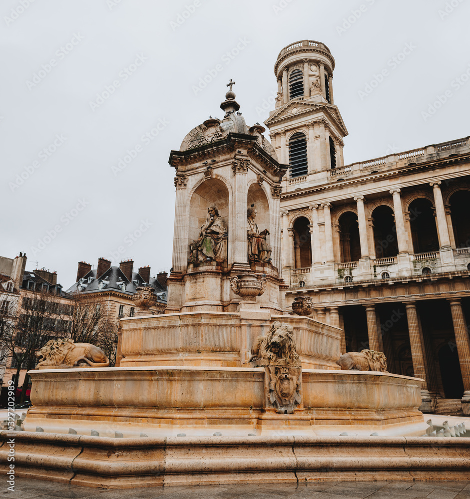 The Roman Catholic Church of Saint-Sulpice in Paris, France. Square with a fountain in front of the facade. Sculptures of saints and lions adorn the fountain.