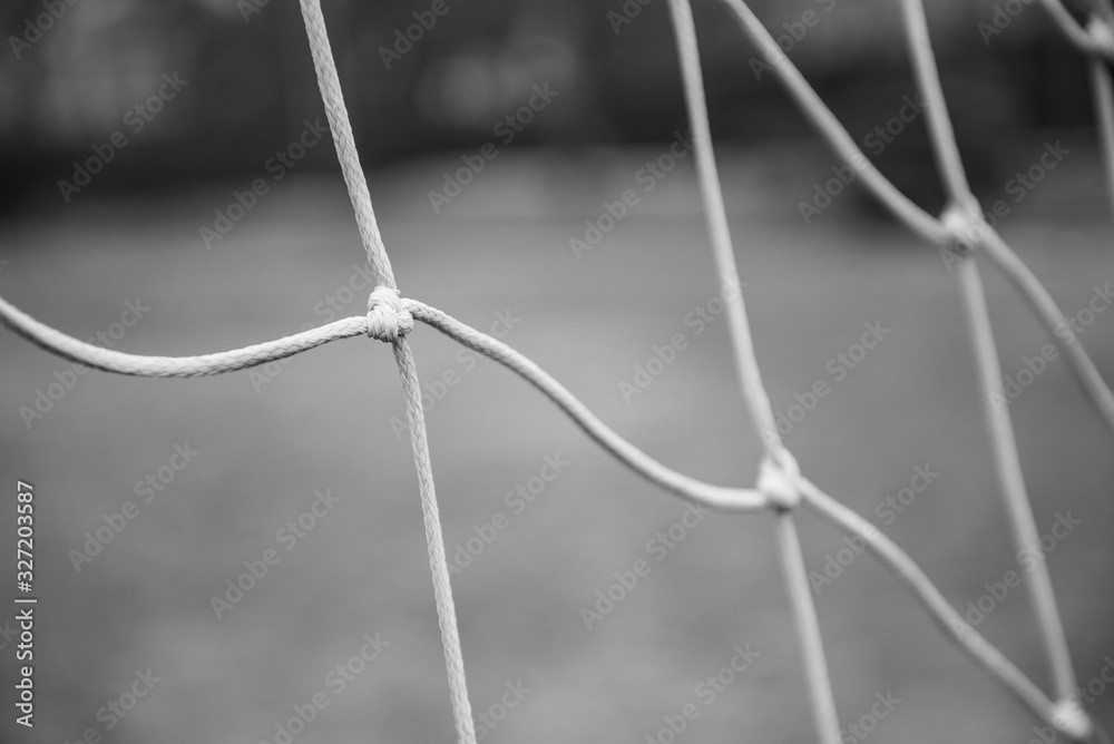 Close up of a football net. A knot in the foreground in focus, the rest blurred. Monochrome Close up of a football net. A knot in the foreground in focus, the rest blurred. Monochrome