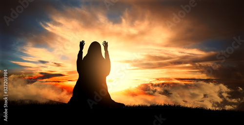 Fototapeta silhouette of a Muslim woman praying at sunset
