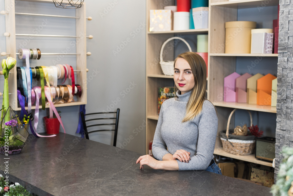 Woman florist stands at the reception in a flower shop. Small business representative Woman florist stands at the reception in a flower shop. Small business representative