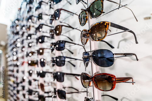 Sunglasses on display shelves in glasses store. Sales rack of glasses.