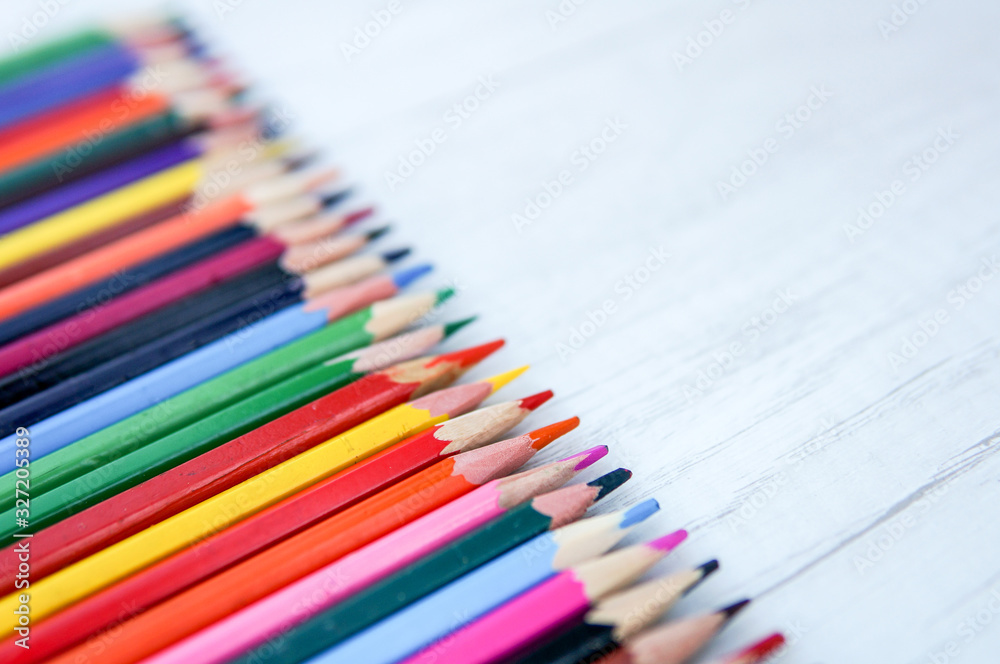Multicolor sharpened pencils isolated on wooden background in a row Multicolor sharpened pencils isolated on wooden background in a row