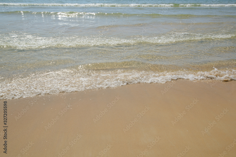 Fluffy sea waves on gold sandy beach. Beautiful crystal water. Fine clean sand. Sunny Tropical seashore on Patong beach, Phuket's west coast, Thailand, Andaman Sea. Summer nature background.