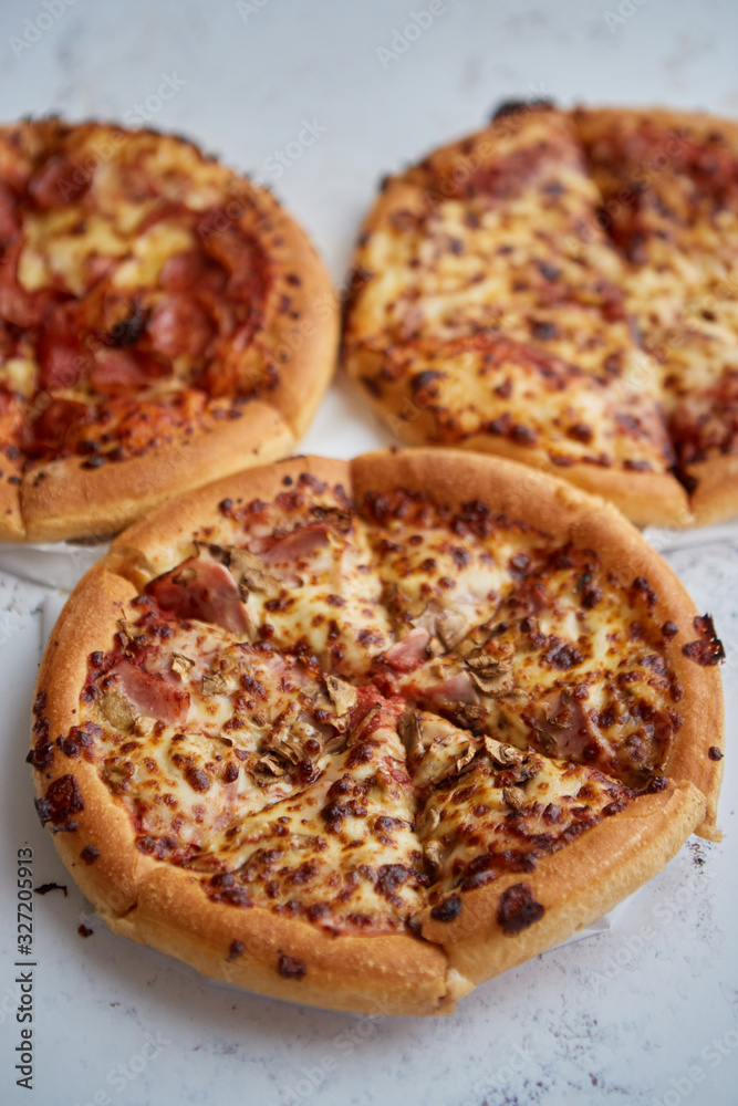 Three american style pizzas served on a table Three american style pizzas served on a table