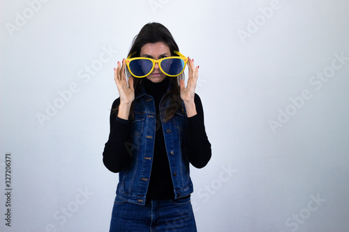 serious  middle age woman with big glasses, long face, with a serious look on his face, isolated on gray background studio shotblack sweater, denim jacket, jeans. Place for your text in copy space. photo