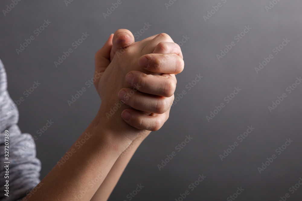 Child hold his hands for pray on grey background. fingers ross Child hold his hands for pray on grey background. fingers ross