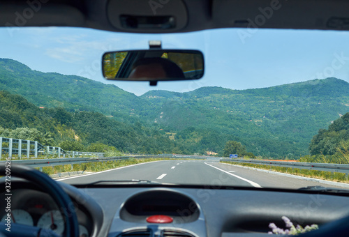 Asphalt highway through a picturesque landscape seen from a car in motion © branislav