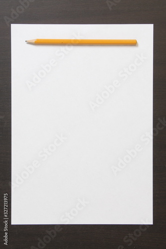 Template of white paper and pencil on dark wenge color wooden background.