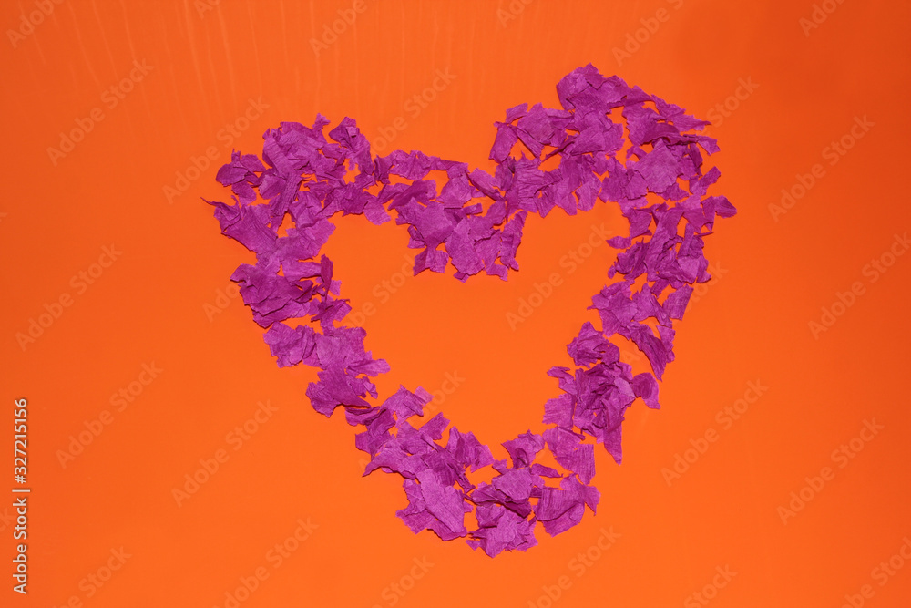 Purple heart on an orange background. A heart made of pieces of paper. Purple heart on an orange background. A heart made of pieces of paper.