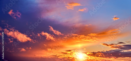 sunset sky landscape background natural color of evening cloudscape panorama with setting sun rays coming through clouds © vaalaa