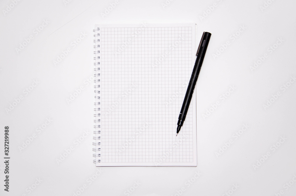 Squared notebook with black pen on a white background. Record ideas, notes, plans, tasks. Notebook top and side view. Flatlay. Copy Space Squared notebook with black pen on a white background. Record ideas, notes, plans, tasks. Notebook top and side view. Flatlay. Copy Space
