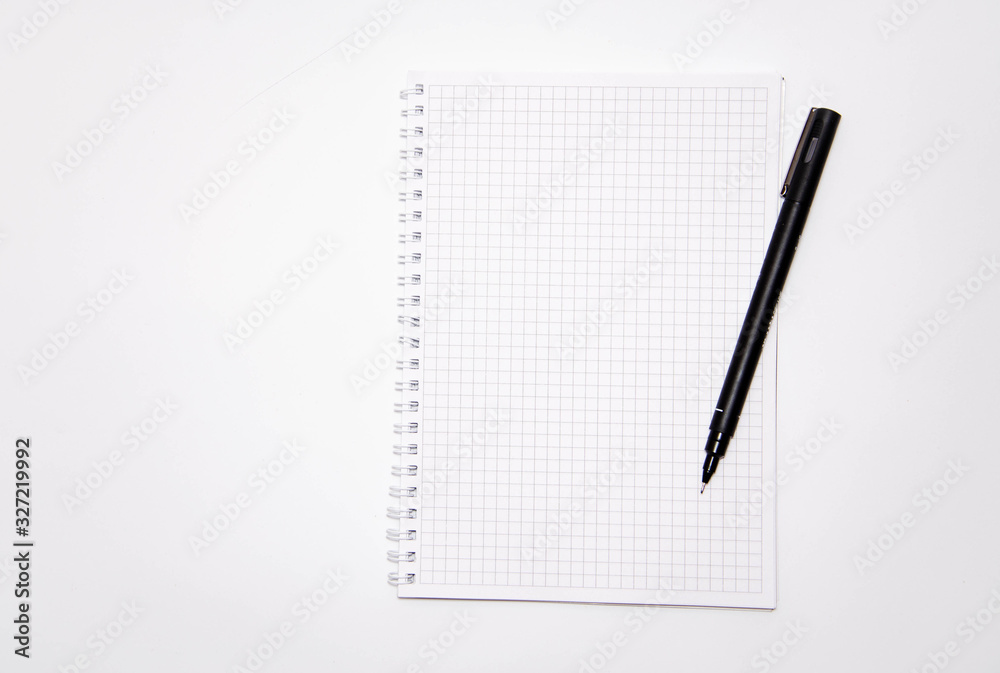 Squared notebook with black pen on a white background. Record ideas, notes, plans, tasks. Notebook top and side view. Flatlay. Copy Space Squared notebook with black pen on a white background. Record ideas, notes, plans, tasks. Notebook top and side view. Flatlay. Copy Space