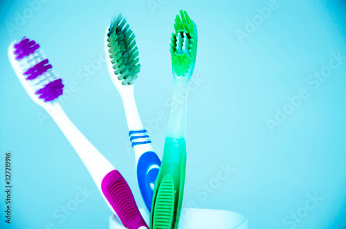 Three brushes for cleaning teeth in a glass white and orange on a blue background. Shaving machines in a glass. Brushes and machine tools in one glass on a blue background.Copy Space