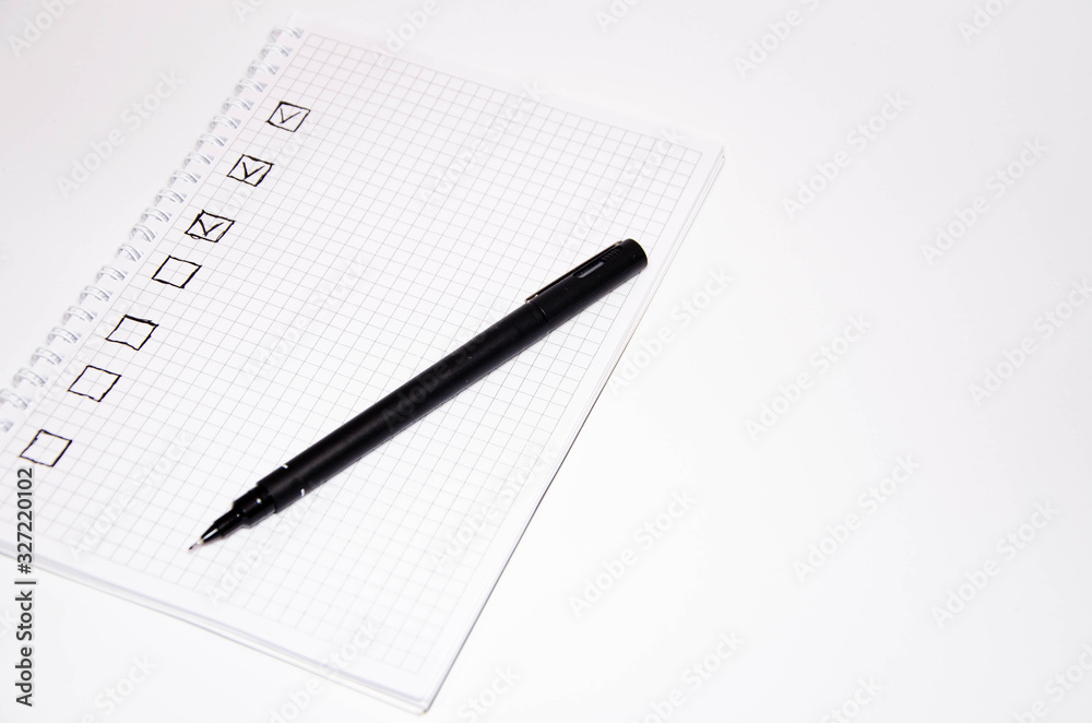 Check list. Square items are empty and checked with a tick. Squared notebook with black pen on a white background. Record ideas, notes, plans, tasks. Copy Space Check list. Square items are empty and checked with a tick. Squared notebook with black pen on a white background. Record ideas, notes, plans, tasks. Copy Space