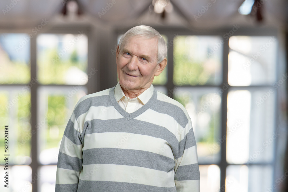 Portrait of very old man is smiling. Caucasian senior grandfather in striped sweater. Windows background. Portrait of very old man is smiling. Caucasian senior grandfather in striped sweater. Windows background.