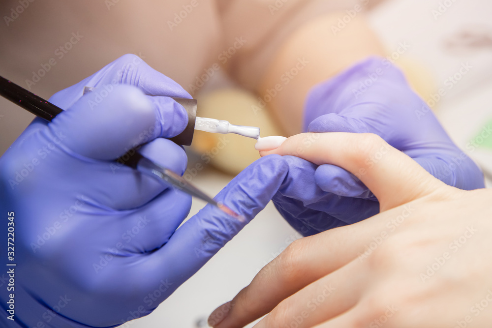 Macro photo manicure drop of varnish, master applies gel with brush on nails of girl Macro photo manicure drop of varnish, master applies gel with brush on nails of girl