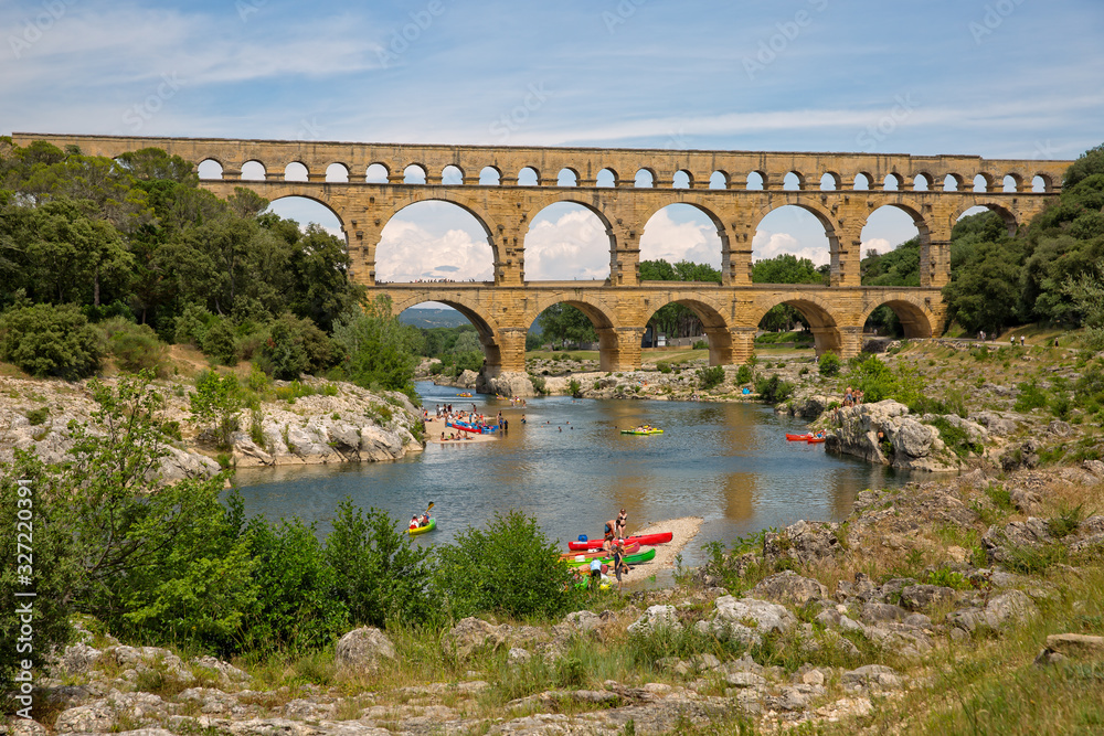 Kayaking under the 2000 year old Roman aqueduct. People kayaking on the Gardon river at the Pont du Gard, an ancient Roman aqueduct, near Nimes, Gard, Provence, France