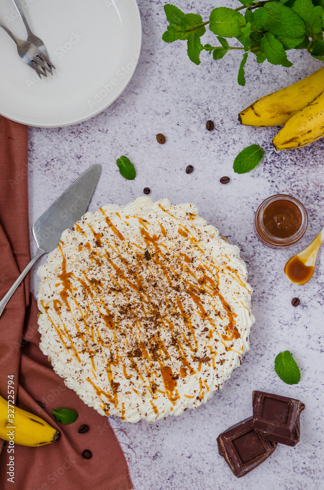Traditional Banoffee pie with fresh bananas, whipped cream, chocolate, coffee and toffee. No baking dessert. Vertical orientation. Top view.