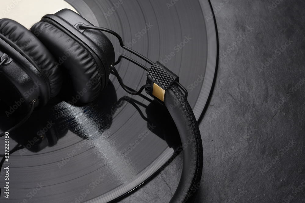 Over or on-ear headphones on vinyl record. - obrazy, fototapety, plakaty 