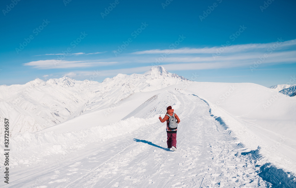 Skier makes photo on top of snowy mountain at nice sun day. Caucasus Mountains in winter, Georgia, region Gudauri.
