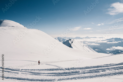 A skier goes skiing from the top of the mountain on a beautiful sunny day. Caucasus mountains in winter, Georgia, Gudauri region, Mt. Kudebi.
