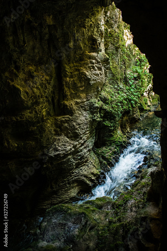 waterfall in deep forest with whitewater flowing into cave