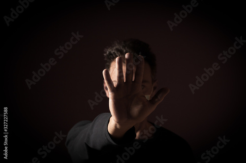 Portrait of  sick caucasian man with medical mask and stop hand. Coronavirus Covid-19 concept. Black background 