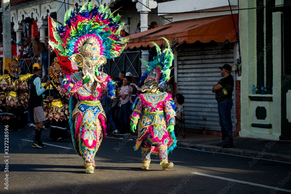 family in colorful carnival elephant costumes walk by city street at dominican parade family in colorful carnival elephant costumes walk by city street at dominican parade